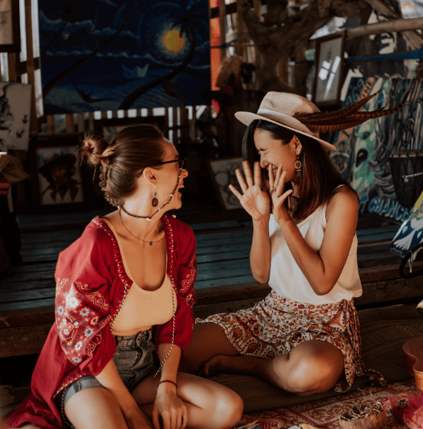 Two women sitting on the floor and laughing together.
