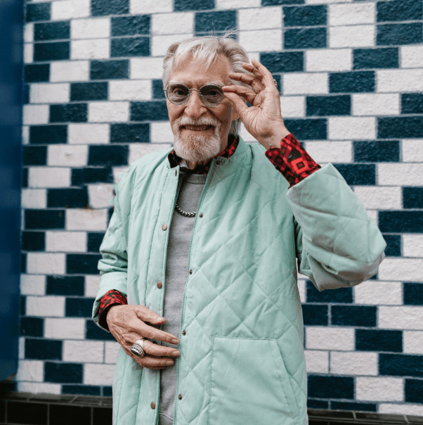 Older man in stylish glasses posing in the street.